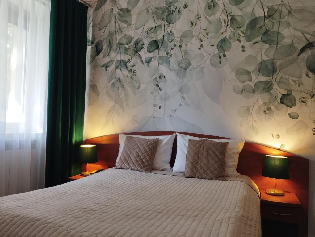 Pokój hotelowy Złotego Lina z łóżkiem i roślinną tapetą